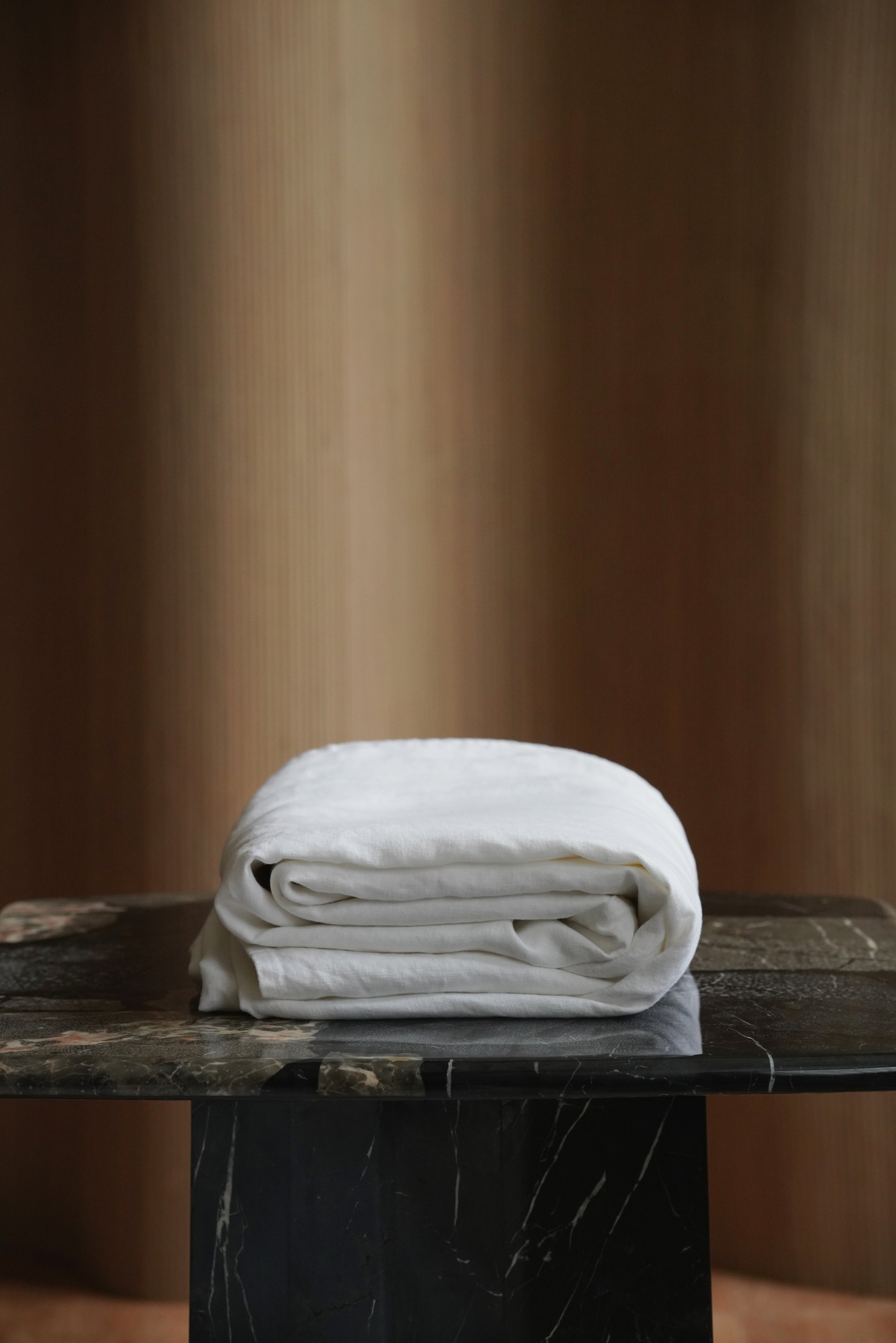 Folded stack of premium white 100% European flax linen bedspreads showing thick 350 GSM heavyweight texture.