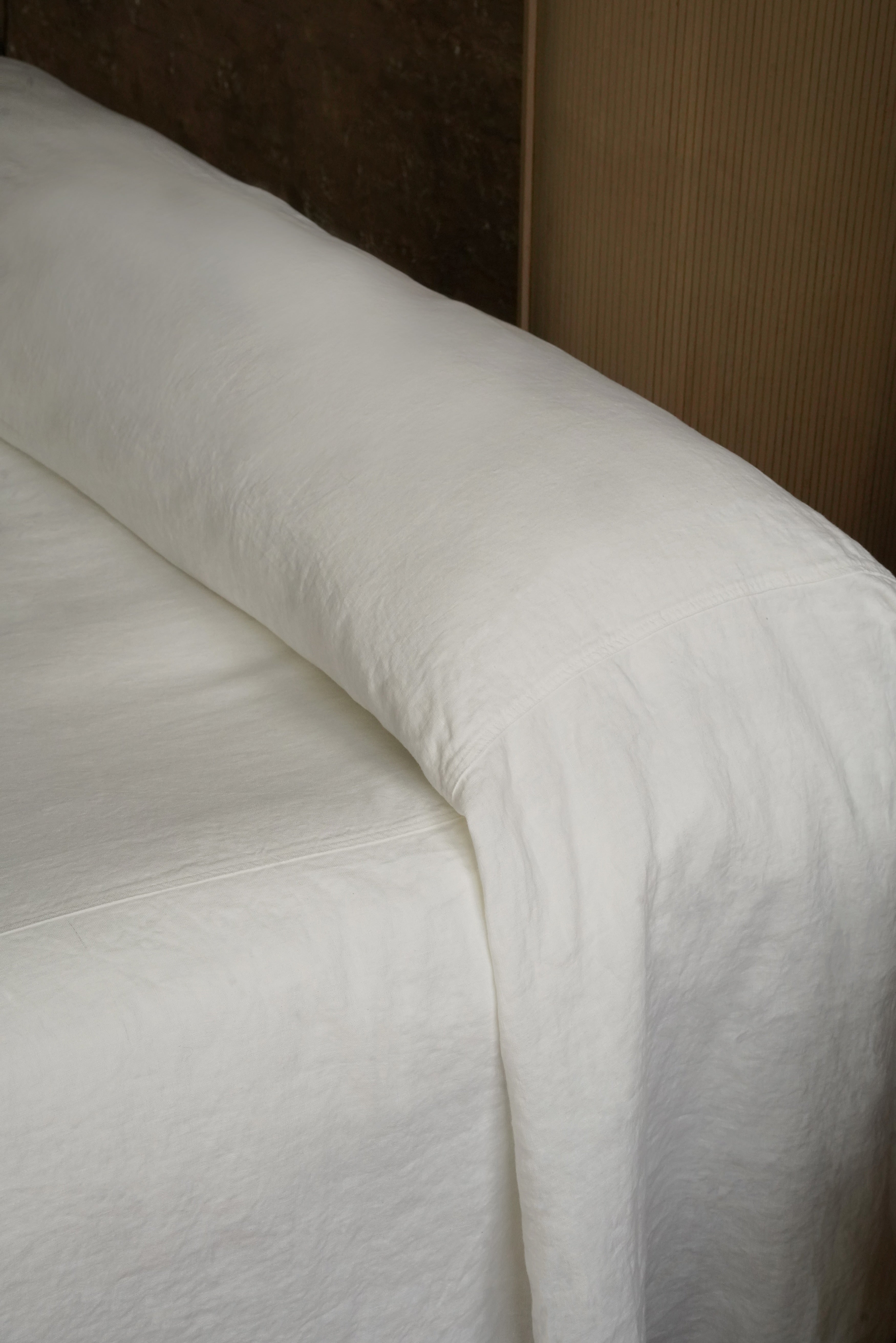 etail shot of white linen bedding "puddling" on the floor, perfect for Japandi and modern coastal bedroom decor
