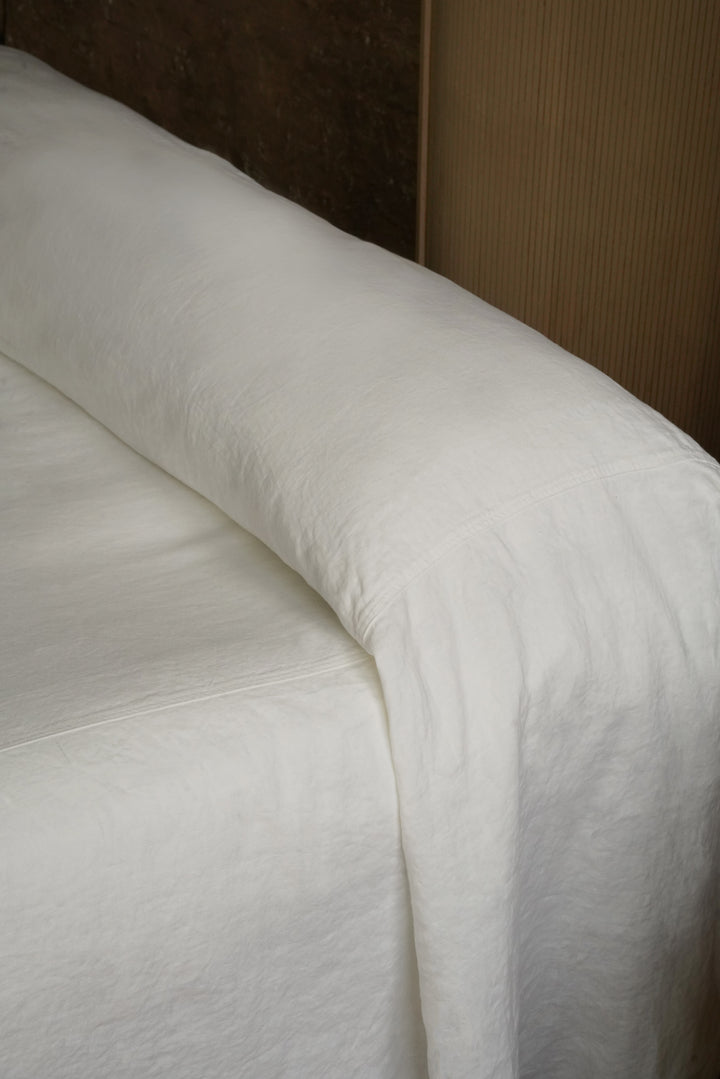 etail shot of white linen bedding "puddling" on the floor, perfect for Japandi and modern coastal bedroom decor
