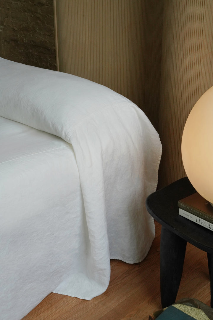 Side view of a white heavyweight linen bedcover showing the elegant drape and seamless minimalist design
